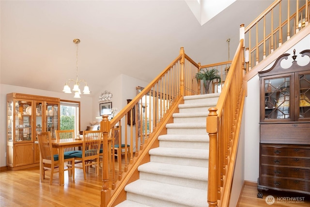 staircase with wood finished floors and an inviting chandelier