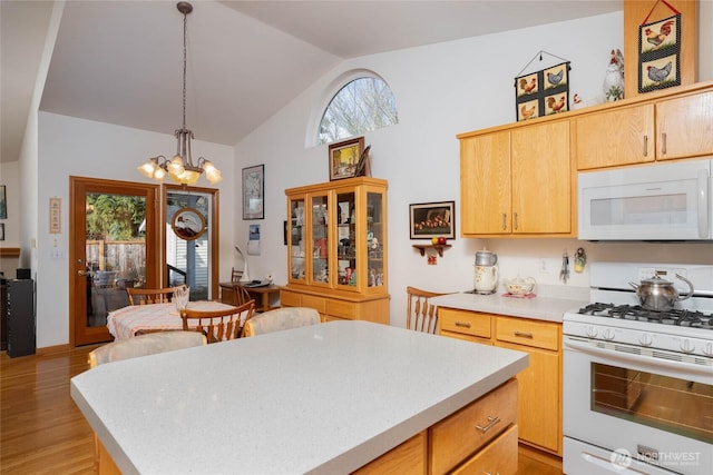 kitchen with lofted ceiling, light wood-style flooring, white appliances, light countertops, and an inviting chandelier