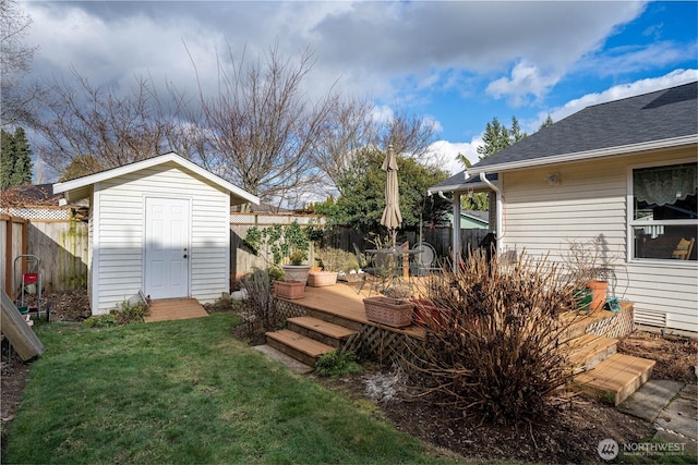 view of yard featuring an outbuilding, a deck, fence, and a storage unit