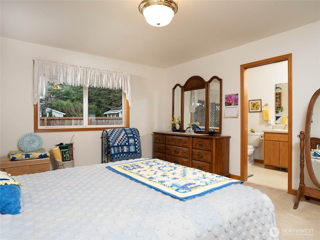 bedroom with baseboards, light carpet, and ensuite bath