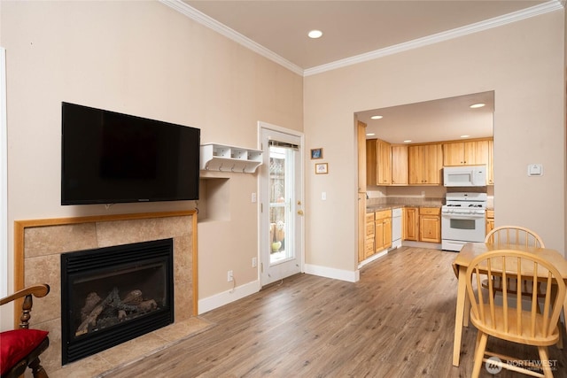 living area with recessed lighting, light wood-style flooring, a tiled fireplace, ornamental molding, and baseboards