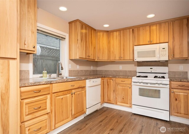 kitchen featuring wood finished floors, white appliances, a sink, and recessed lighting