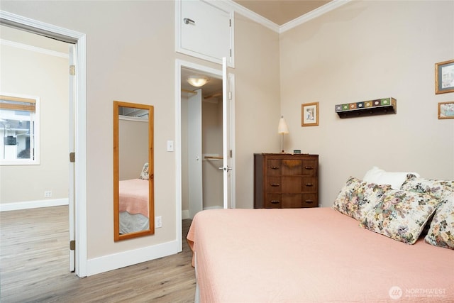 bedroom with light wood-type flooring, crown molding, and baseboards