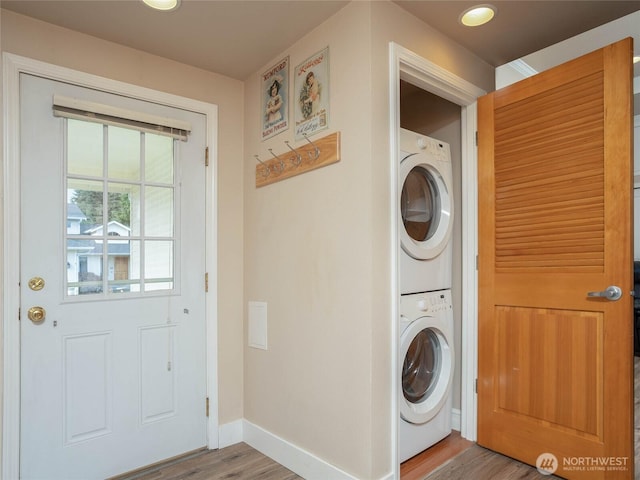 washroom with laundry area, baseboards, wood finished floors, and stacked washer and clothes dryer