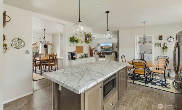 kitchen featuring a healthy amount of sunlight, appliances with stainless steel finishes, pendant lighting, and wood finish floors