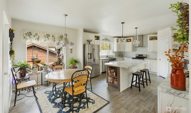 kitchen featuring open shelves, stainless steel appliances, tasteful backsplash, light wood-style floors, and wall chimney exhaust hood