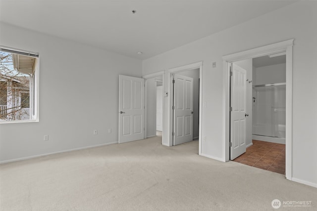 unfurnished bedroom featuring ensuite bathroom, baseboards, and carpet floors