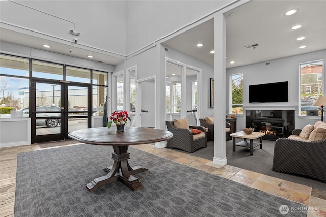 foyer entrance featuring visible vents, a glass covered fireplace, recessed lighting, french doors, and a high ceiling