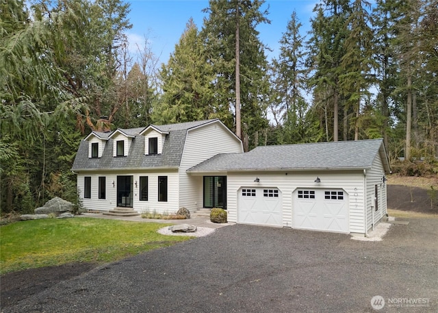 colonial inspired home featuring a gambrel roof, aphalt driveway, roof with shingles, a front yard, and an attached garage