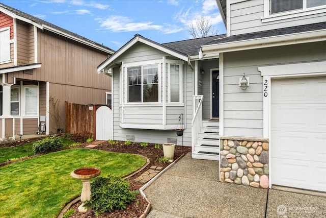 view of exterior entry with crawl space, an attached garage, a yard, and roof with shingles