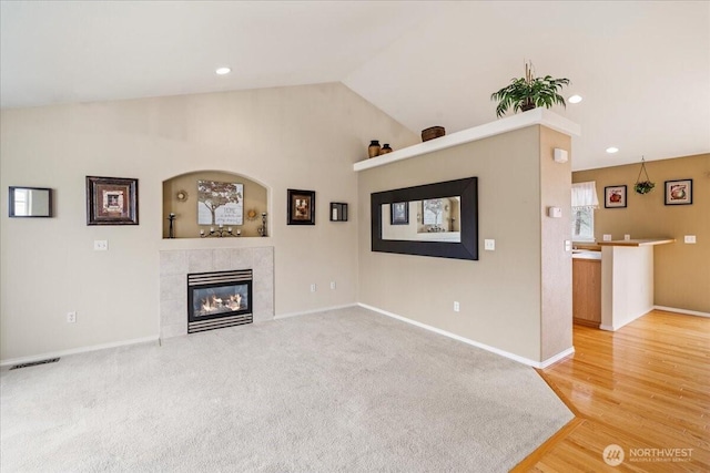 unfurnished living room with visible vents, baseboards, lofted ceiling, recessed lighting, and a tile fireplace