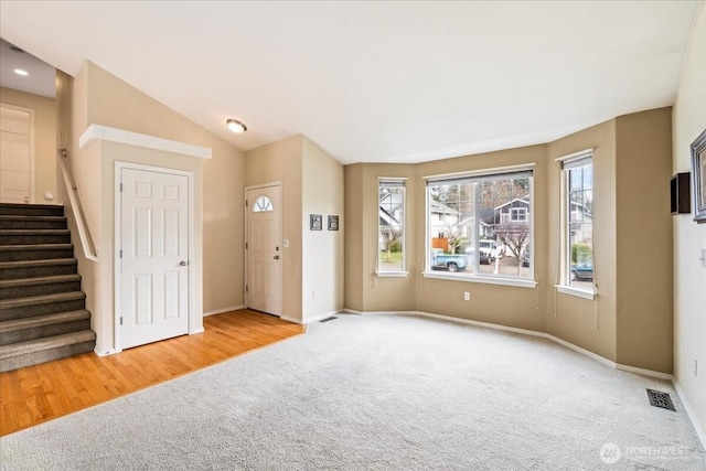 interior space with stairs, lofted ceiling, baseboards, and visible vents