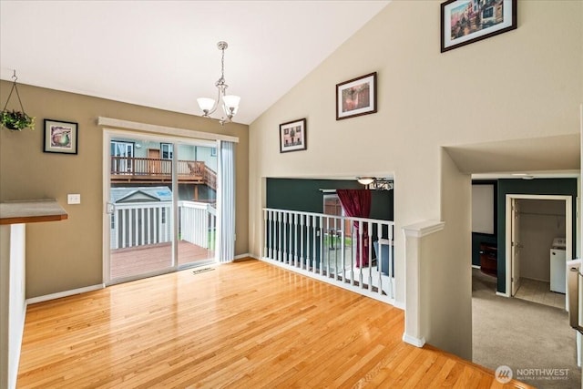 unfurnished dining area featuring visible vents, baseboards, an inviting chandelier, wood finished floors, and washer / clothes dryer