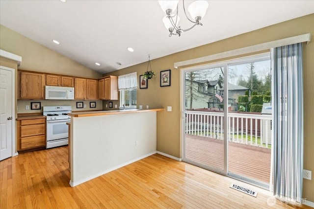 kitchen featuring visible vents, white appliances, plenty of natural light, and lofted ceiling