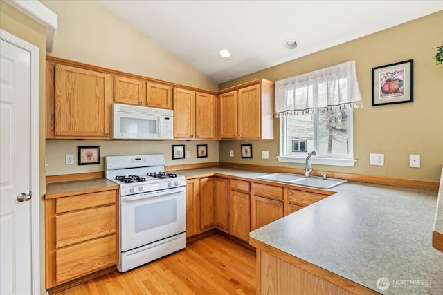 kitchen featuring lofted ceiling, recessed lighting, light wood-style floors, white appliances, and a sink