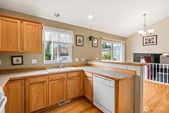 kitchen with visible vents, a sink, light wood-style floors, a peninsula, and dishwasher