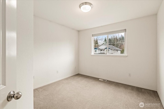 spare room with carpet flooring, baseboards, and visible vents