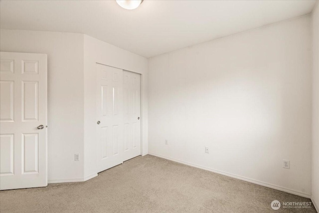 unfurnished bedroom with light carpet, baseboards, and a closet