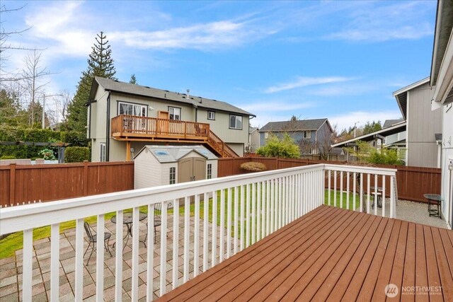 deck with an outbuilding, a fenced backyard, a residential view, and a shed