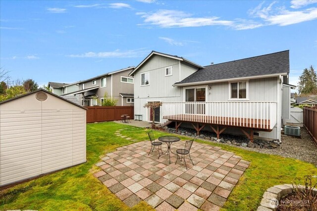 back of property with a lawn, a patio, a fenced backyard, a shed, and an outdoor structure