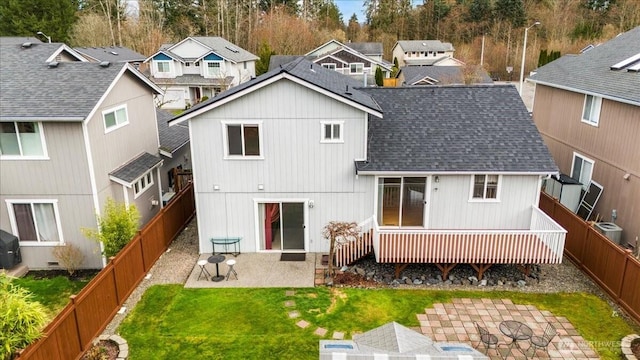 back of house featuring a lawn, a fenced backyard, a residential view, and a shingled roof