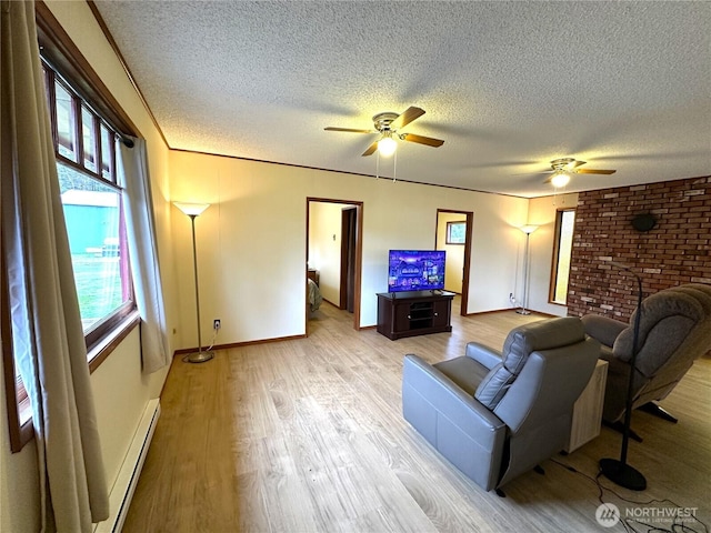 living room with light wood-type flooring, a baseboard heating unit, and a ceiling fan