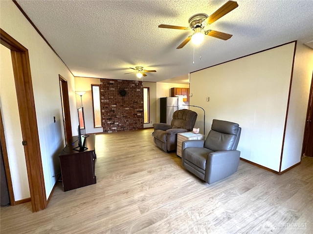 living area featuring crown molding, a textured ceiling, light wood-type flooring, and a ceiling fan