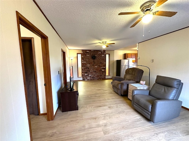 living room with crown molding, a textured ceiling, light wood-type flooring, and ceiling fan