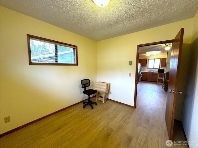 interior space featuring wood finished floors, baseboards, and a textured ceiling