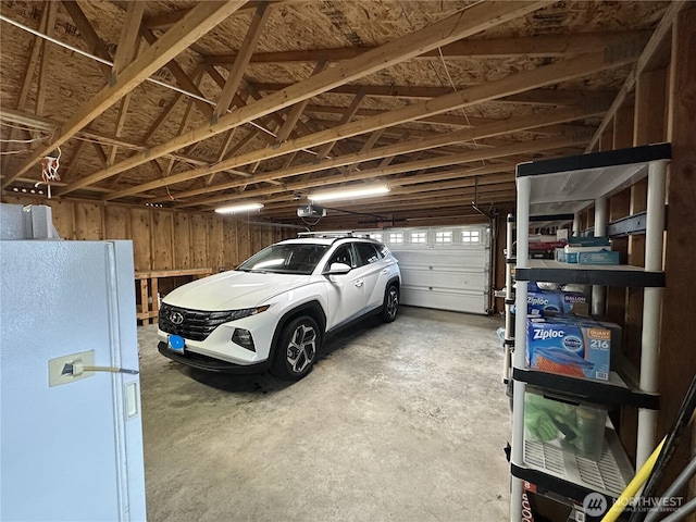 garage with a garage door opener and freestanding refrigerator