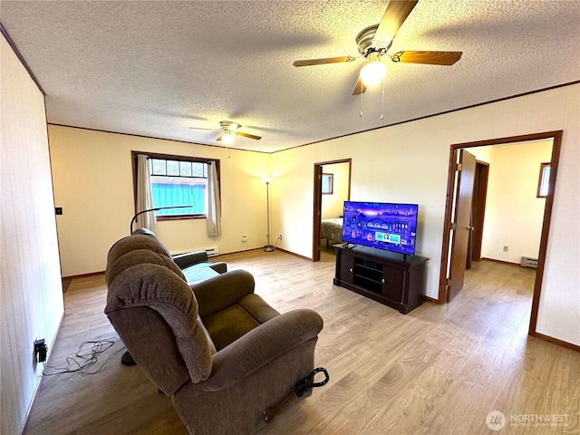 living area with baseboards, ceiling fan, baseboard heating, wood finished floors, and a textured ceiling