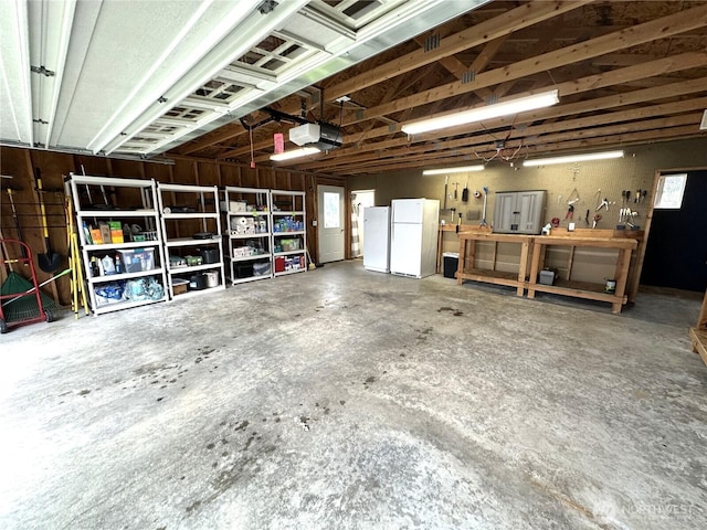 garage with a workshop area, a garage door opener, and freestanding refrigerator