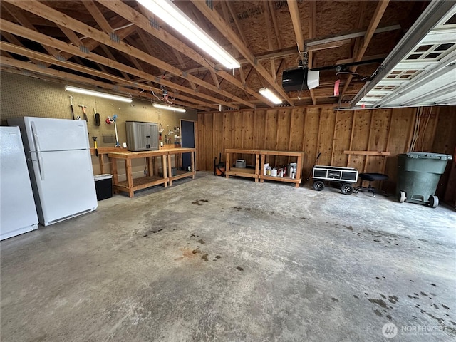 garage with a workshop area, a garage door opener, and freestanding refrigerator