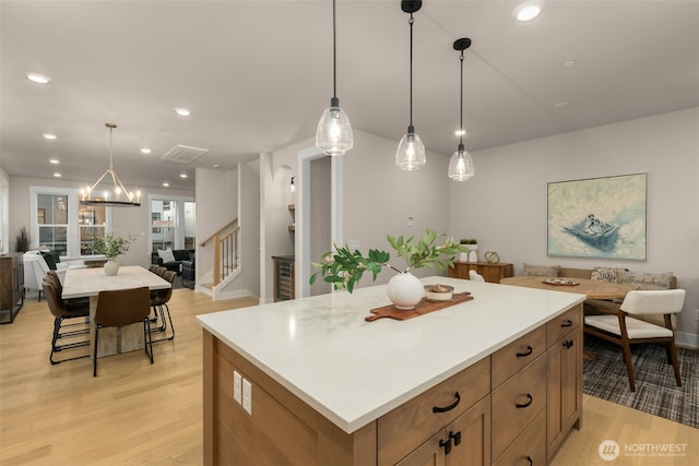 kitchen with recessed lighting, light countertops, light wood-style floors, open floor plan, and a kitchen island