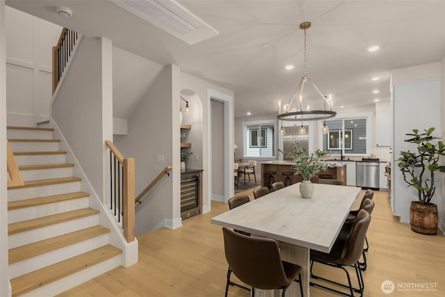 dining area featuring stairs, light wood finished floors, wine cooler, and recessed lighting