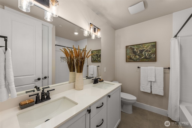 full bathroom featuring double vanity, a sink, toilet, and baseboards