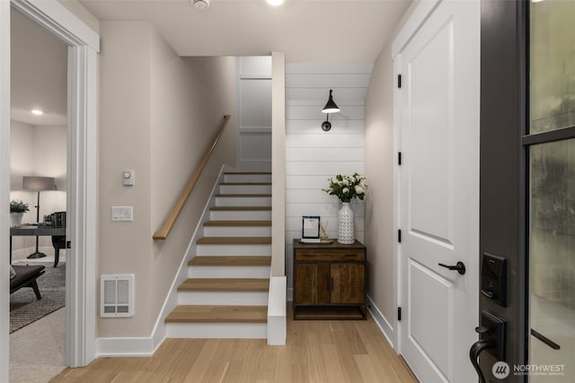 staircase with baseboards, visible vents, and wood finished floors