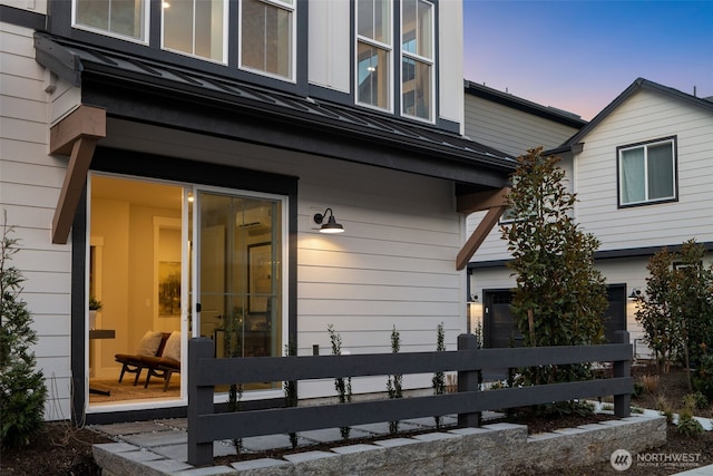 rear view of house with a garage, a standing seam roof, fence, and metal roof