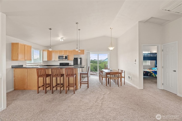 kitchen featuring light carpet, light brown cabinets, stainless steel microwave, dark countertops, and fridge