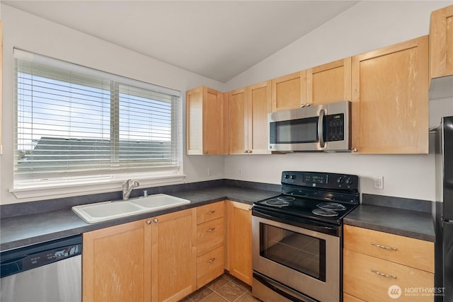 kitchen featuring light brown cabinetry, appliances with stainless steel finishes, dark countertops, and a sink