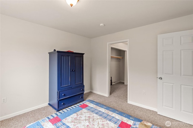 bedroom featuring a spacious closet, light colored carpet, and baseboards