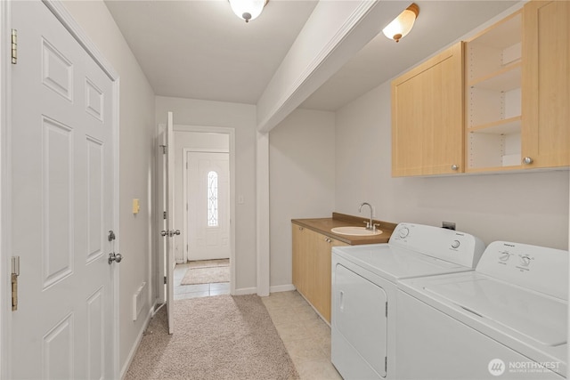 clothes washing area featuring a sink, cabinet space, light tile patterned floors, baseboards, and washing machine and clothes dryer