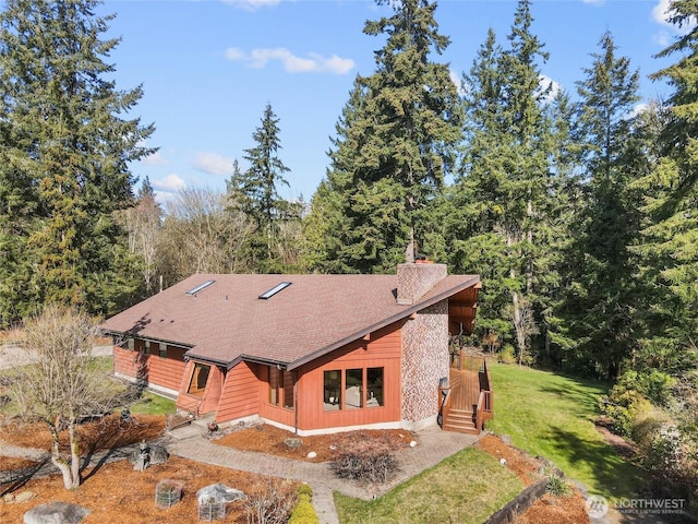 exterior space featuring a yard and a shingled roof