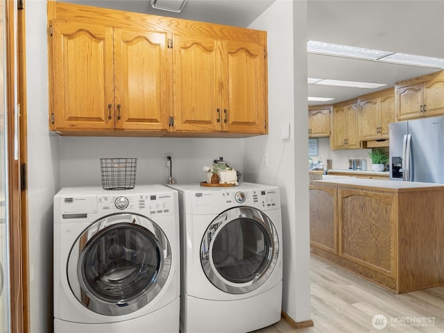 clothes washing area with washer and clothes dryer, laundry area, and light wood finished floors