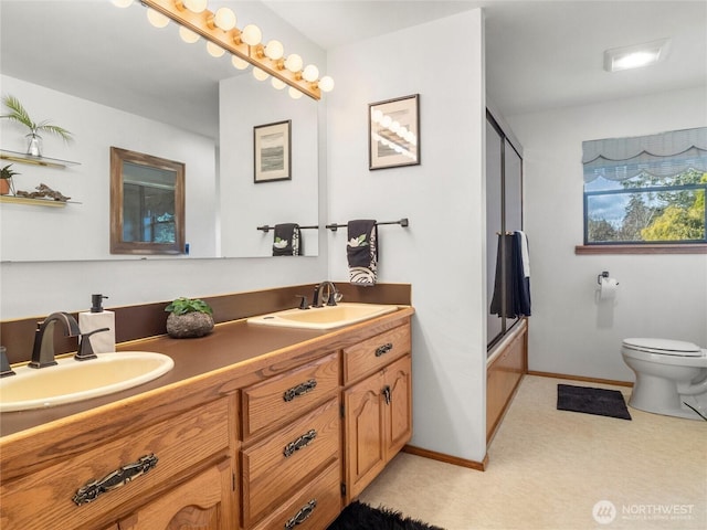 full bath featuring a sink, baseboards, toilet, and double vanity