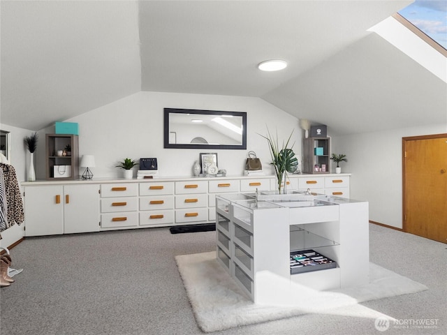 kitchen featuring vaulted ceiling with skylight, white cabinets, carpet flooring, and light countertops