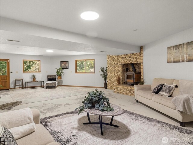 living area featuring visible vents, light colored carpet, a wood stove, and baseboards