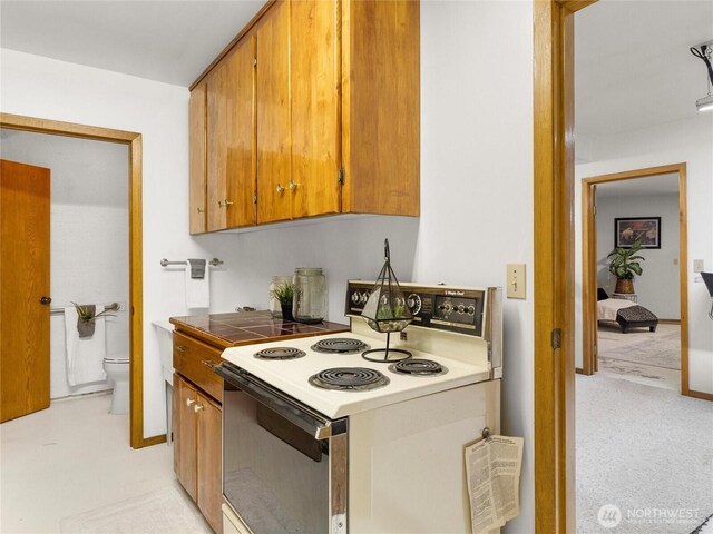 kitchen with white electric range, brown cabinets, light carpet, and tile countertops