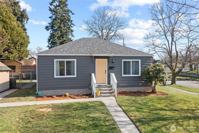 bungalow-style home featuring roof with shingles, a front yard, fence, and a gate