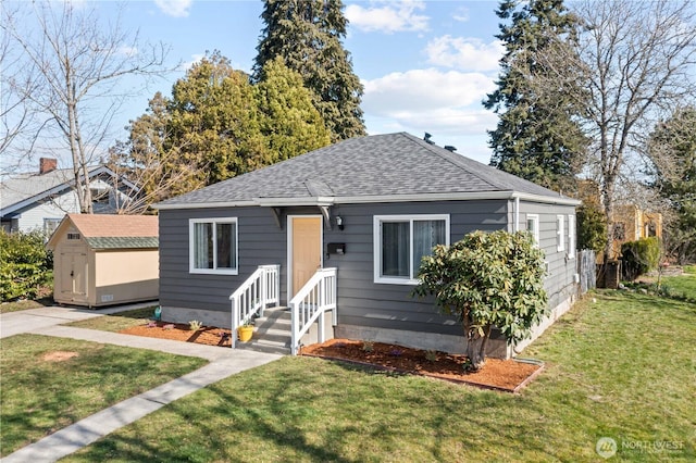 bungalow-style home with an outdoor structure, a storage unit, a front lawn, and roof with shingles